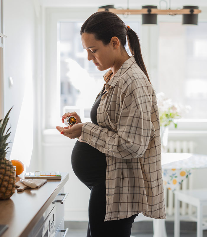 Young pregnant woman taking pills